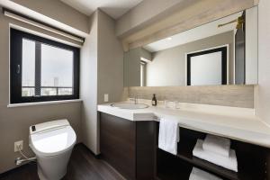 a bathroom with a toilet and a sink and a mirror at the b namba-kuromon in Osaka