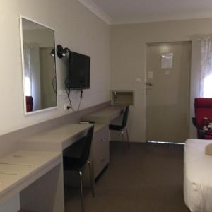 a hotel room with a desk and a mirror at Casino Motor Inn in Casino