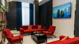a living room with red chairs and a tv at Garnet Mir Hotel in Tashkent