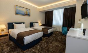 um quarto de hotel com duas camas e uma secretária em Garnet Mir Hotel em Tashkent