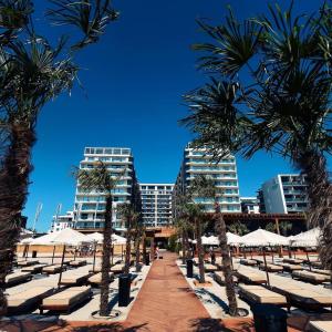 Mamaia Beach Condos 2 في نافوداري: شاطئ فيه نخيل ومظلات بيضاء ومباني
