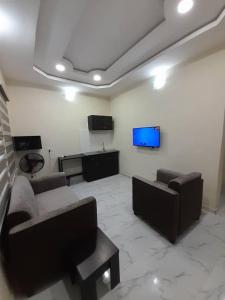 ein Wohnzimmer mit Sofas und einem Flachbild-TV in der Unterkunft F and B serviced apartment Abeokuta in Aro