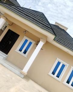 a house with a black roof and two windows at F and B serviced apartment Abeokuta in Aro