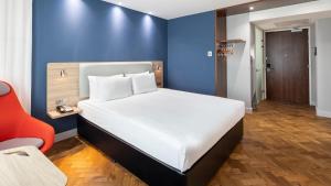 una camera con un letto bianco e una parete blu di Holiday Inn Express Amsterdam - Sloterdijk Station by IHG ad Amsterdam Altre 31 foto