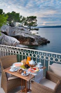 un tavolo con cibo su un balcone vicino all'acqua di Hotel Sunceva Postelja Brela a Brela