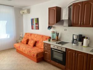 uma sala de estar com um sofá laranja na cozinha em Holiday Apartments 4 Bozhurets Kavarna Bulgaria em Bozhurets