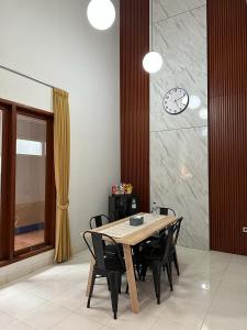 a dining room table with chairs and a clock on a wall at Villa Magnifica by REQhome in Ciater-hilir