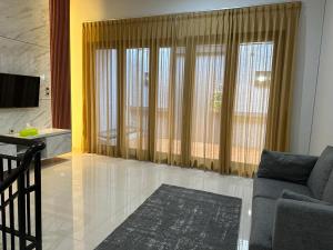 a living room with a couch and large windows at Villa Magnifica by REQhome in Ciater-hilir