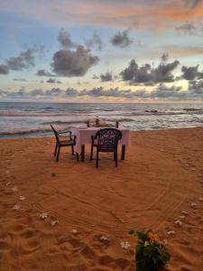 una mesa y sillas sentadas en la playa en Dreamvillage en Dodanduwa