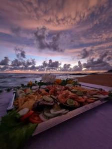 een dienblad met eten op een strand met de oceaan bij Dreamvillage in Dodanduwa