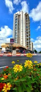 a tall building with flowers in front of a street at stylish apartment by the SEA in Ashdod