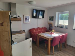 a small kitchen with a table and a red couch at Der Landhof Wildrose in Stolpe