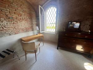 een kamer met een bureau, een dressoir en een raam bij B&B Antica cascina in Boretto