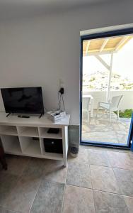 uma sala de estar com uma televisão e uma janela em Gioia’s view em Loutrá