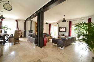 a living room with couches and a clock on the wall at La Lézarde, chambre d'hôte, piscine, salle d'eau privatif, café ou thé offert le matin in Saint-Victor-la-Coste +24 photos