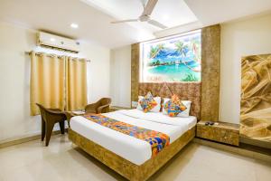 a bedroom with a bed and a desk and a painting at FabExpress Apollo I in Ahmedabad