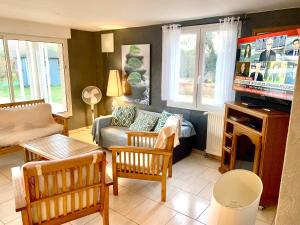 a living room with a couch and a tv at Maison charmante à Saint-Géry avec piscine partagée in Saint-Géry