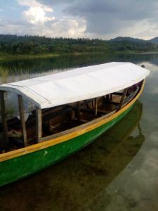 a green boat with a white roof sitting in the water at Imuhira Campsites&CBT in Macuba