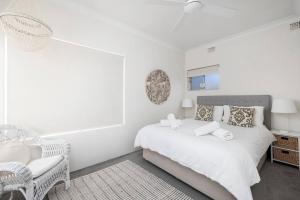 a white bedroom with a bed and a chair at Bayview Towers 10 in Nelson Bay