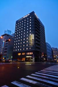 een hoog zwart gebouw in een stadsstraat 's nachts bij Dormy Inn Premium Nagoya Sakae in Nagoya