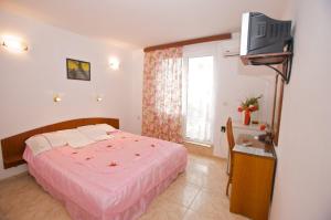 1 dormitorio con 1 cama y TV en la pared en Family Hotel Orfei, en Nesebar