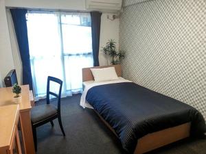 a bedroom with a bed and a desk and a chair at HOTEL LiVEMAX BUDGET Fuchu in Fuchu