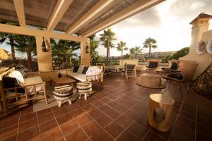 a patio with chairs and tables and palm trees at Alcaidesa Boutique Hotel in La Alcaidesa