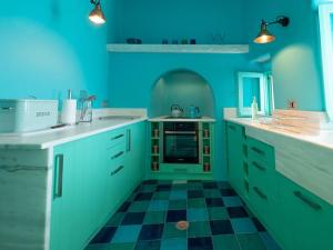 a blue kitchen with a black and white checkered floor at Aegean Garden Apartment in Kardhianí