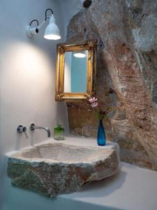 a bathroom with a stone sink and a mirror at Aegean Garden Apartment in Kardhianí
