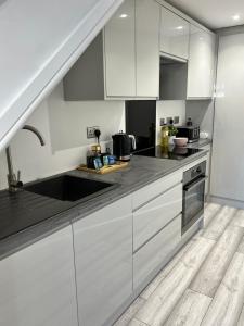 uma cozinha com armários brancos e um lavatório em The Wedge em Southend-on-Sea
