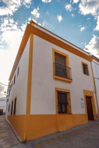 - un bâtiment blanc et orange avec des fenêtres dans l'établissement 3 bedrooms house with city view balcony and wifi at Sevilla Penaflor, à Peñaflor