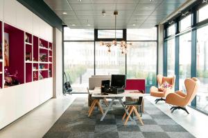 ein Büro mit einem Schreibtisch, Stühlen und einem Tisch in der Unterkunft Moxy Frankfurt Eschborn in Eschborn