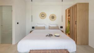 a bedroom with a large white bed with a bench at Nove Milos Luxury by Estia in Pollonia +53 photos