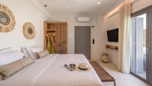 a bedroom with a bed with a hat and a television at Nove Milos Luxury by Estia in Pollonia