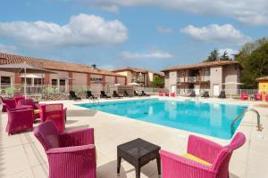 uma piscina com cadeiras e uma mesa ao lado de um edifício em Les bords de l'Aveyron em Nègrepelisse