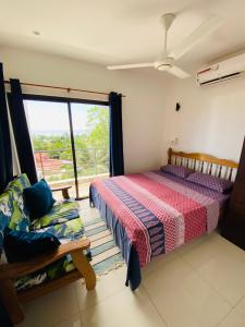 a bedroom with a bed and a couch and a window at Oceanic View Lodges in Bel Ombre