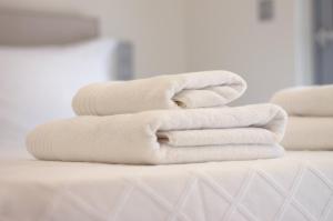 4 toallas blancas apiladas encima de una cama en Cottage Boutique Apartments Athens, en Atenas