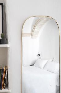 Cette chambre blanche dispose d'un miroir et d'une étagère. dans l'établissement CALMAPIANTA home for green lovers, à Putignano