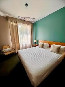 a bedroom with a large white bed with a window at Hôtel de la Marine in Saint-Herblain