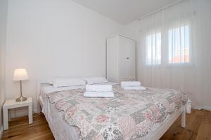 a white bedroom with a bed and a window at Apartment Nikola in Kastel Novi