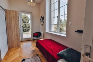 1 dormitorio con 1 cama roja y 2 ventanas en Domaine Grand Piquecaillou - Appartement Bordeaux, 