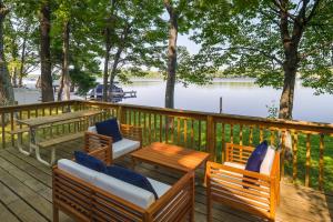 a deck with chairs and tables and a view of the water at Pet-Friendly Kalkaska Cottage on Lake Crawford! in Kalkaska