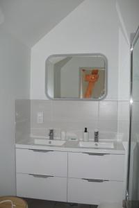 a white bathroom with a sink and a mirror at Gite les Noyers in Noailhac