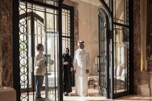 un grupo de personas parados frente a puertas de cristal en Four Seasons Hotel Doha, en Doha