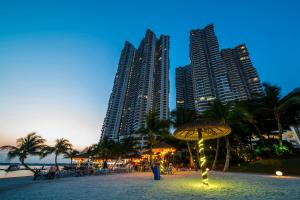a beach with a umbrella and some tall buildings at Country Garden Bay Point 2BR by Hauz Cinta @Danga Bay in Johor Bahru