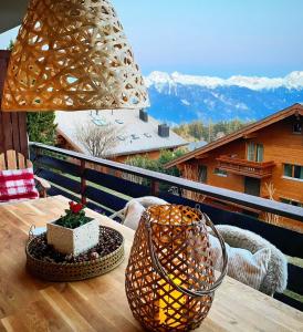 a table with a lamp on a balcony with mountains at Window on Crans Montana, Appartement avec vue sur les Alpes in Crans-Montana