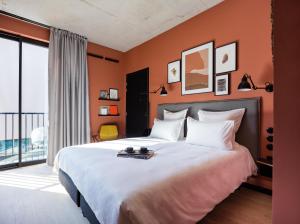 a bedroom with a large bed with orange walls at Deskopolitan House in Paris