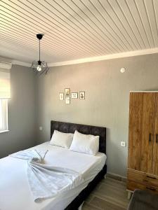 a bedroom with a bed with white sheets and a ceiling at Coconut Apart in Kumluca