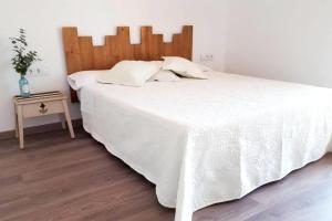 a bedroom with a large white bed with a wooden headboard at Charming Villa in El Vendrell + Pool in El Vendrell +31 photos