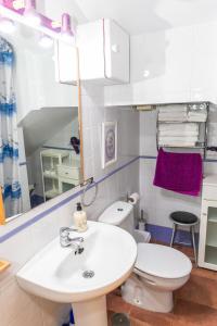 een badkamer met een wastafel, een toilet en een spiegel bij Casa Marinero - Patio Andaluz in Barbate